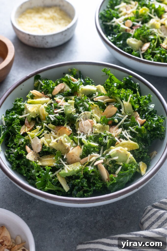 Close-up of kale and Brussels sprouts salad in a bowl, showcasing avocado chunks and toasted almonds.