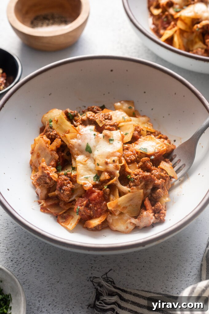Hearty Beef and Cabbage Bake 3 A serving of low carb unstuffed cabbage roll casserole in a white bowl, showing tender cabbage, ground beef, and melted cheese.