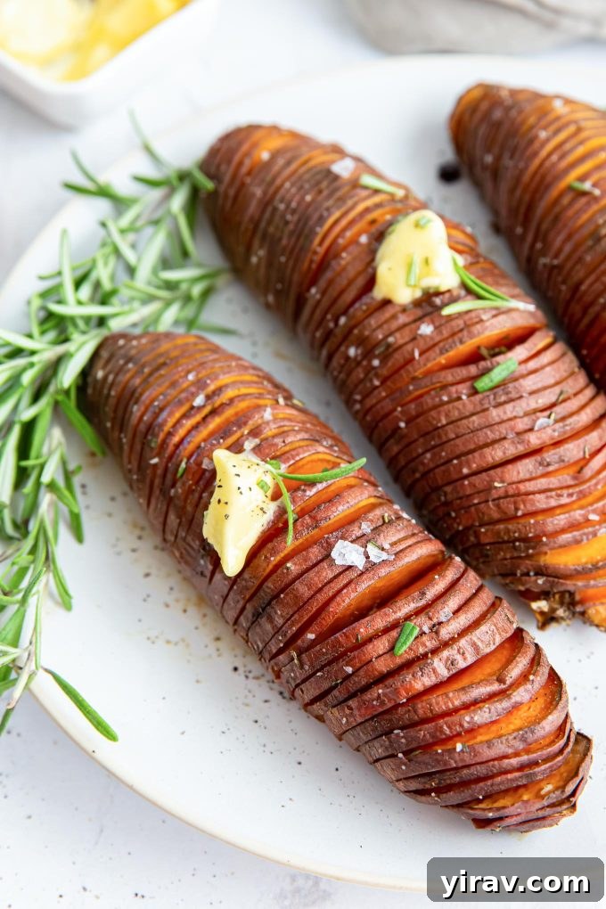 Crispy Hasselback Sweet Potatoes 3 Close-up of Hasselback sweet potatoes on a plate, glistening with butter and fresh rosemary