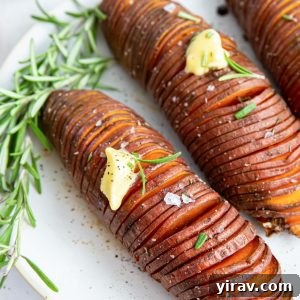 Crispy Hasselback Sweet Potatoes 8 Hasselback sweet potatoes on a plate with butter and rosemary