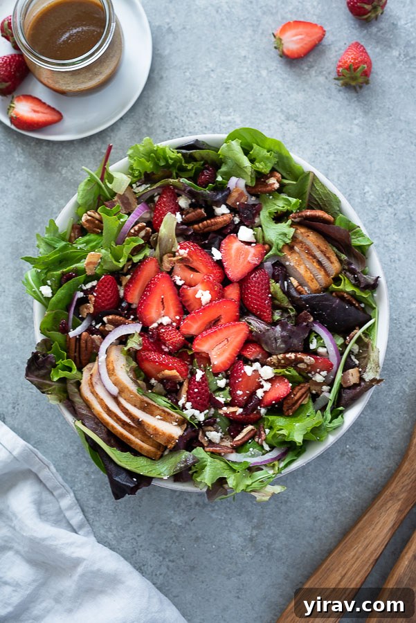 overhead shot of strawberry fields salad in white serving bowl with wooden servers