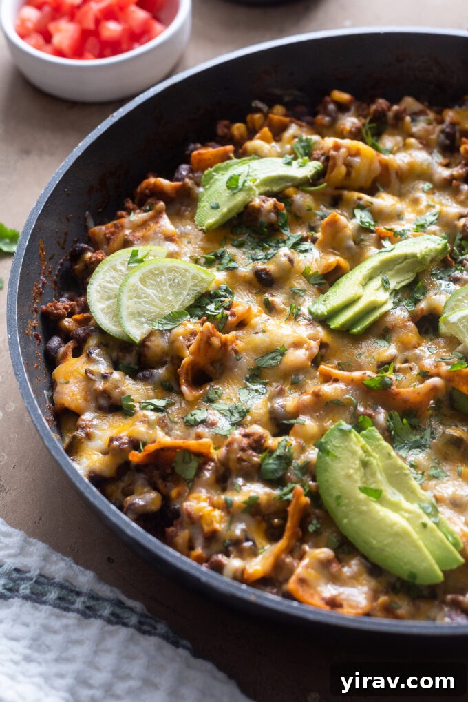 Close-up of a sizzling ground beef enchilada skillet, showcasing the rich sauce, tortilla pieces, and vibrant ingredients.