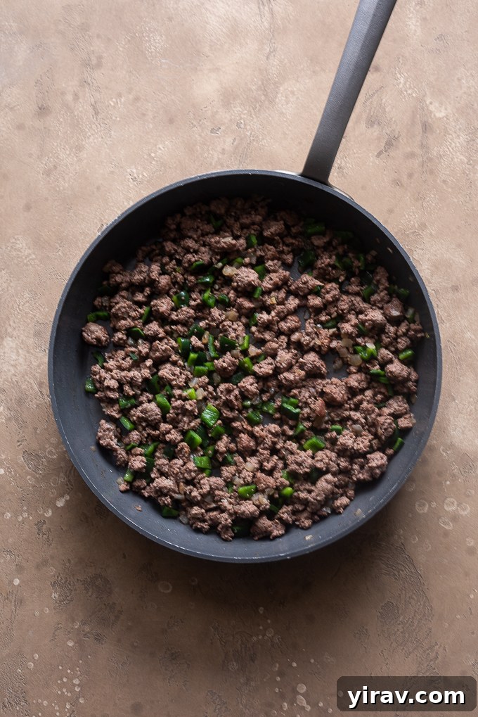 Sautéing chopped onions in a large skillet until translucent, forming the aromatic base for the enchilada casserole.
