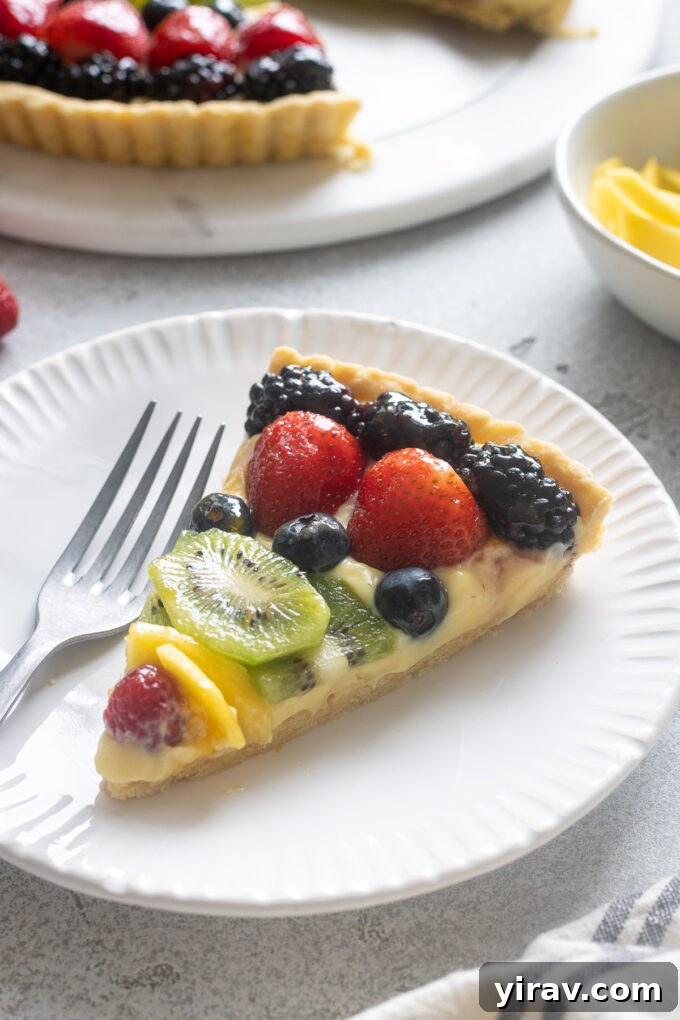 A delectable slice of French fruit tart served on a white plate