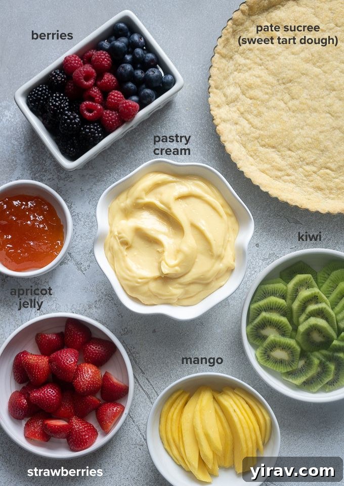 Arrangement of fresh fruit tart ingredients including various berries, kiwi, and mango