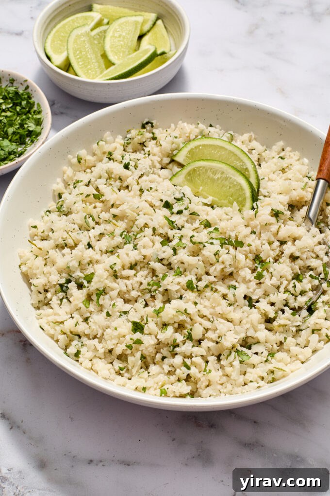 Cilantro lime cauliflower rice in serving bowl with lime wedges on top.