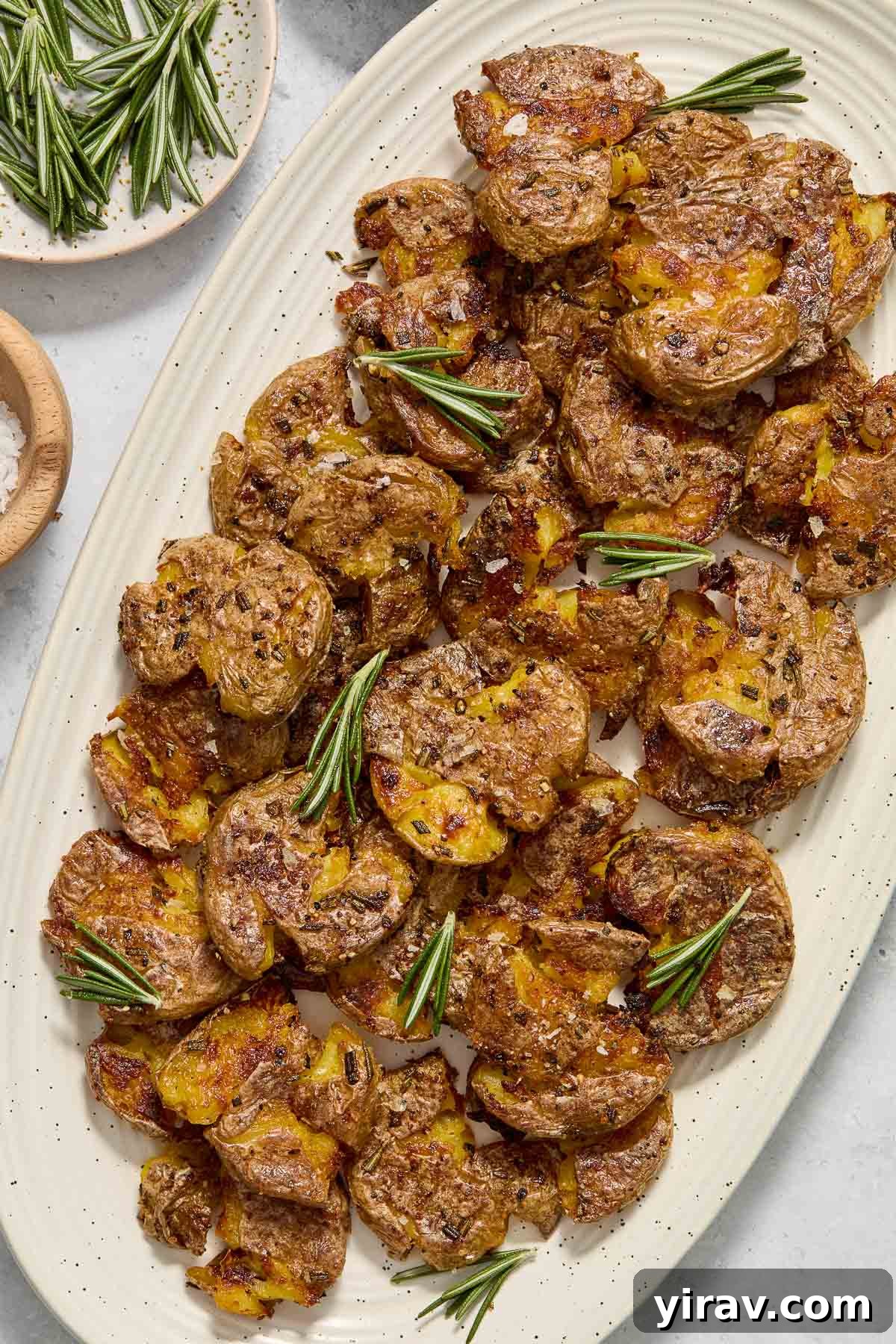 A platter of golden-brown crispy smashed potatoes, beautifully seasoned and ready to serve.