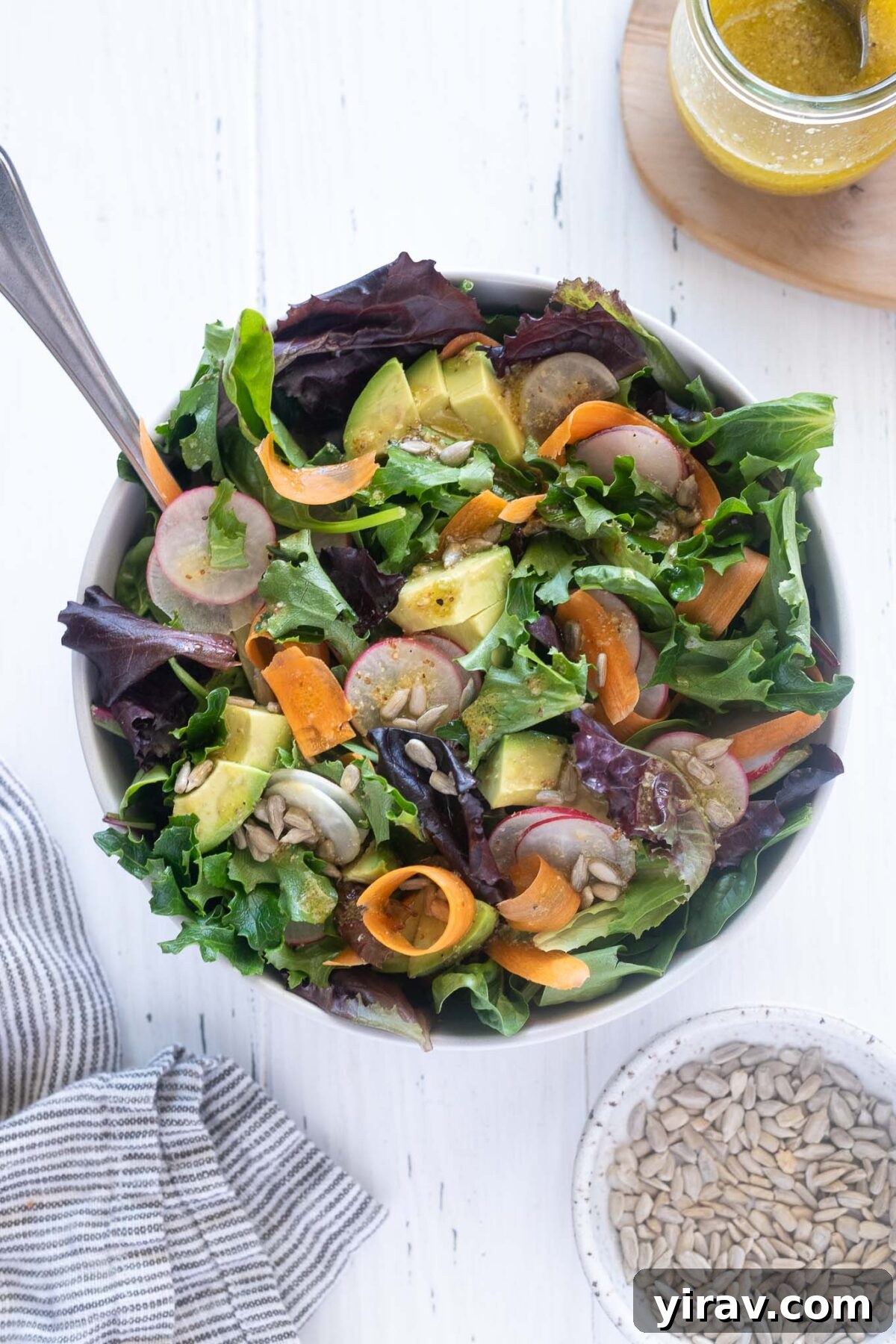 A refreshing Spring Mix Salad in a bowl, with serving spoons inviting you to dig in.