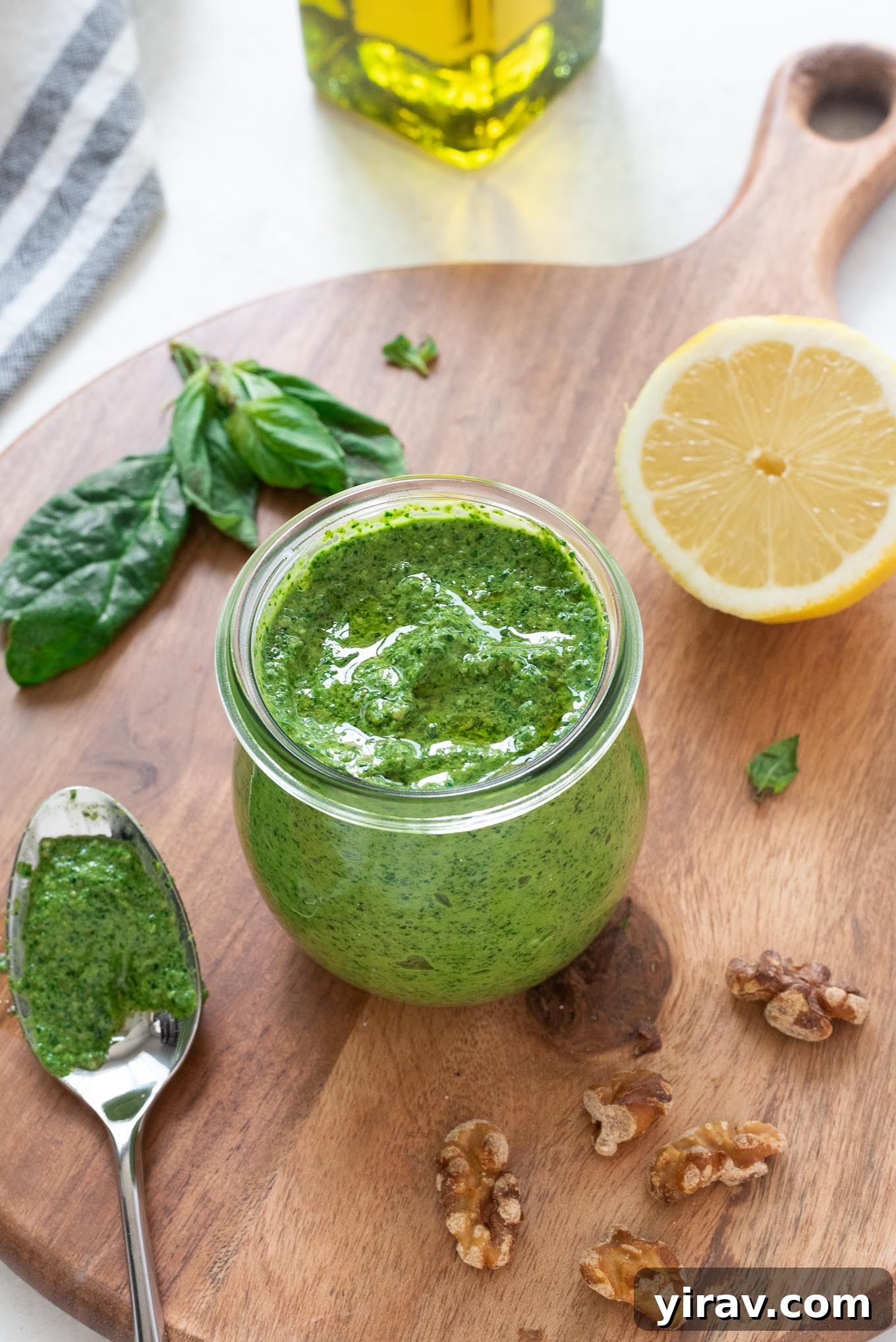 Fresh spinach pesto in a jar, with a glistening layer of olive oil on top, ready for use.