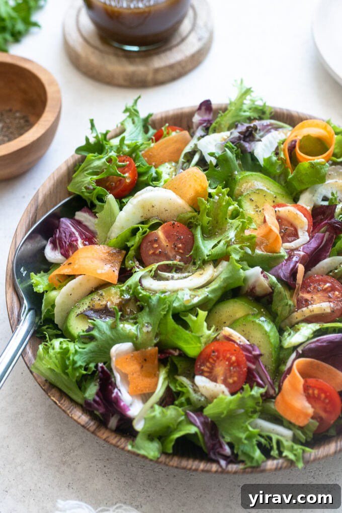 A close-up shot of Insalata Mista in a serving bowl, with a wooden serving spoon gently digging into the fresh, colorful salad.
