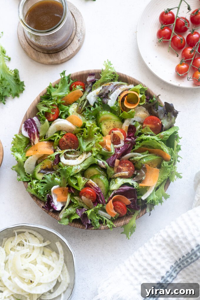 Close-up of Insalata Mista, highlighting the delicate slices of fennel, bright red cherry tomatoes, and a variety of green leaves, all coated in dressing.
