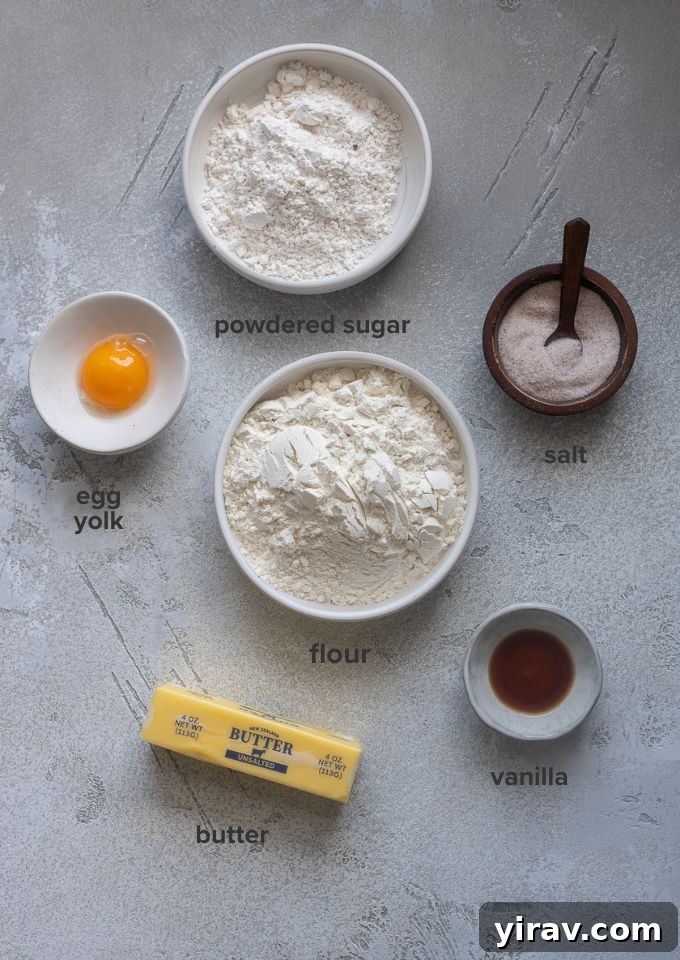 Buttery Sweet Tart Dough 4 Various ingredients for Pate Sucree recipe laid out: flour, butter, powdered sugar, egg yolk, and vanilla extract.