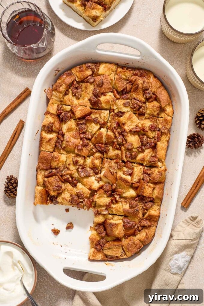 A baked eggnog french toast casserole in a baking dish with one slice removed, revealing the custardy interior.