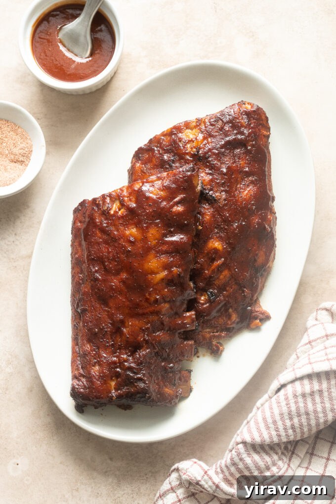 Slow cooker babyback ribs on a platter smothered in barbecue sauce.