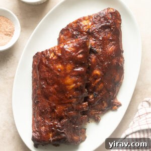 Slow cooker baby back ribs on a platter smothered in barbecue sauce.