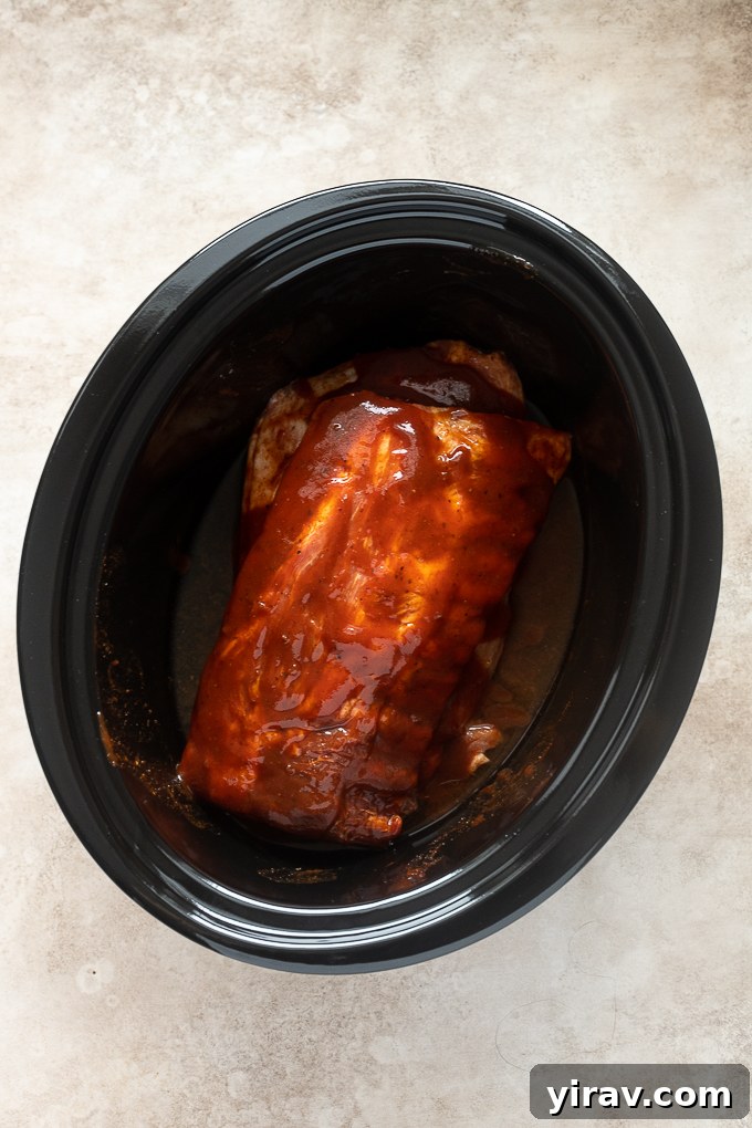Baby back ribs smothered in bbq sauce in slow cooker.