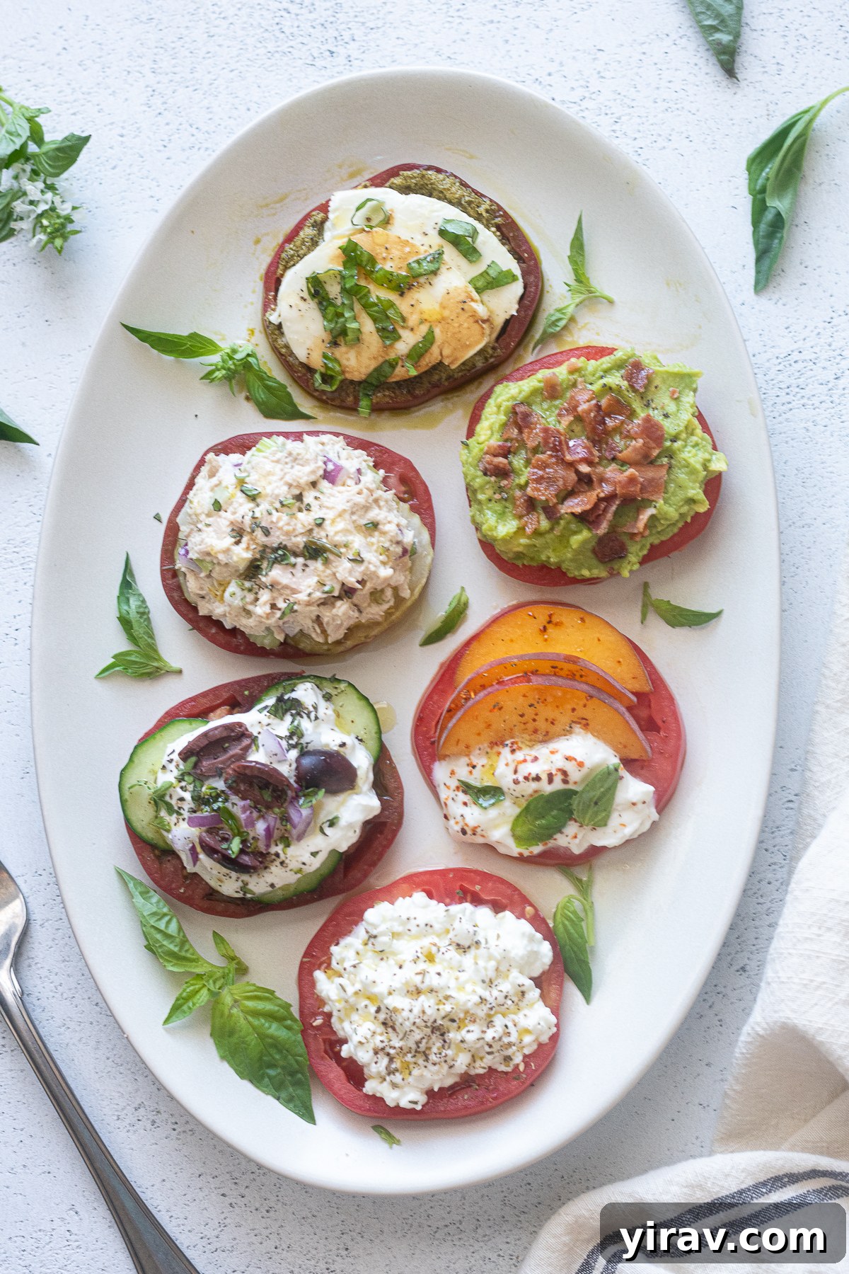 Heirloom tomato flight on a white platter with basil.