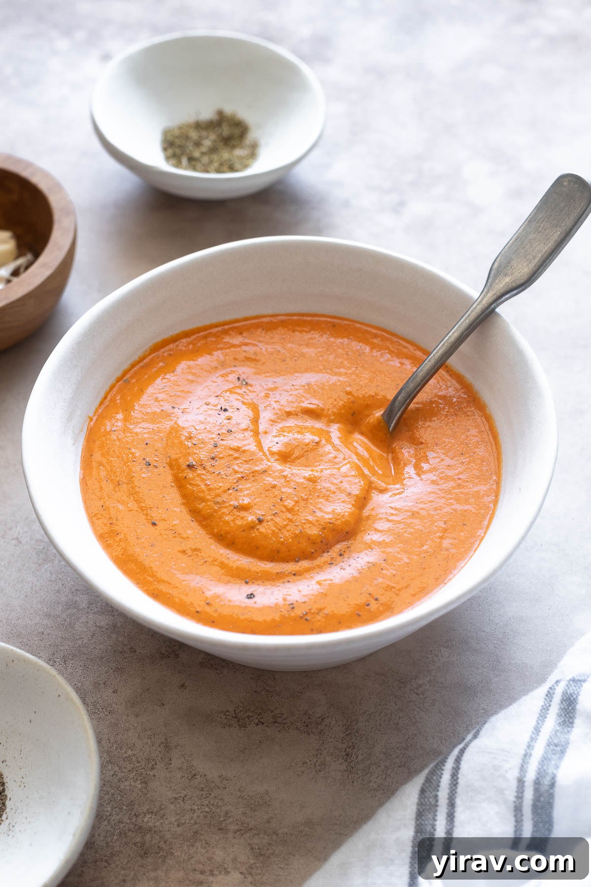 Roasted red pepper sauce in a bowl with a spoon digging in.