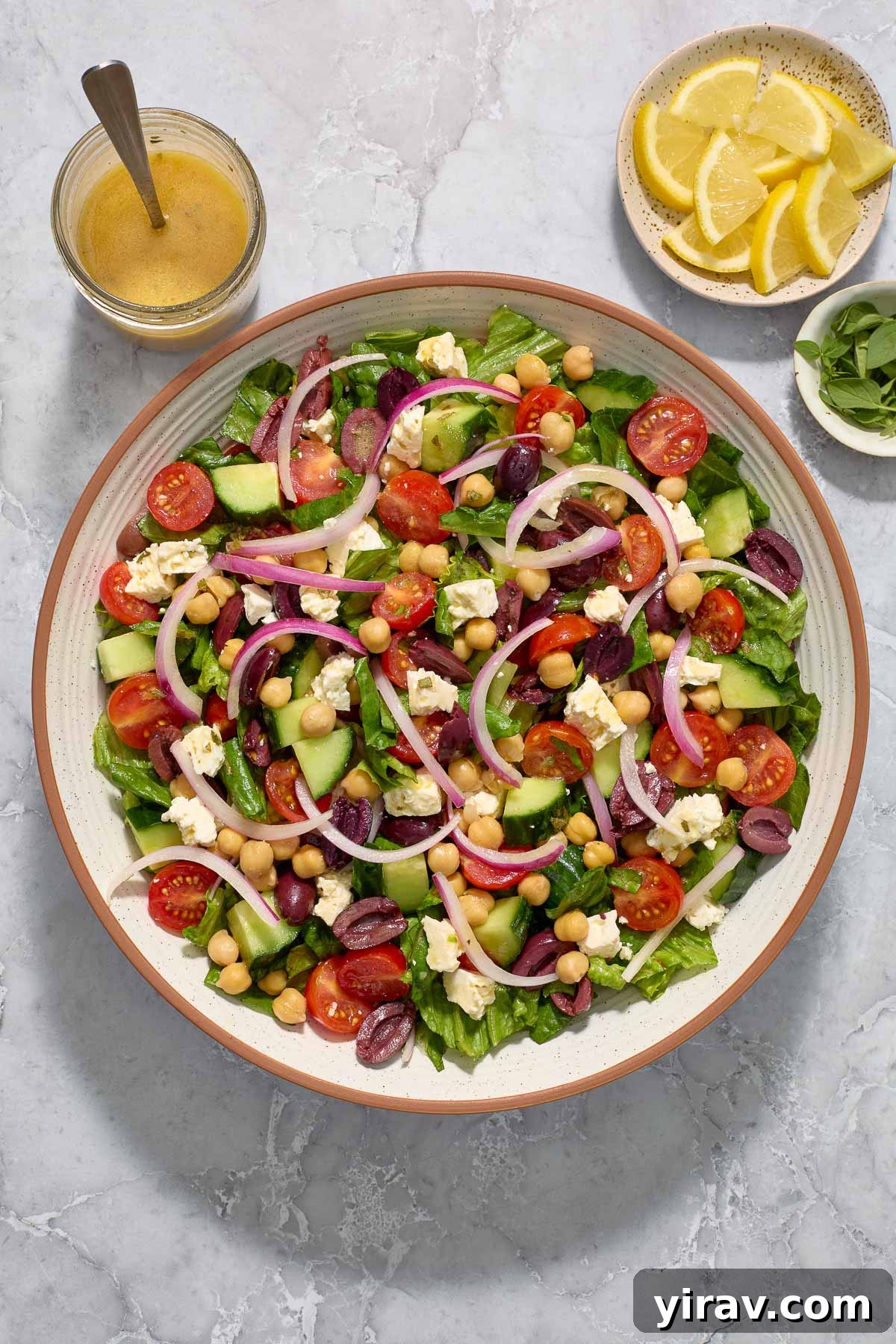 Mediterranean salad in a bowl with Greek dressing alongside.