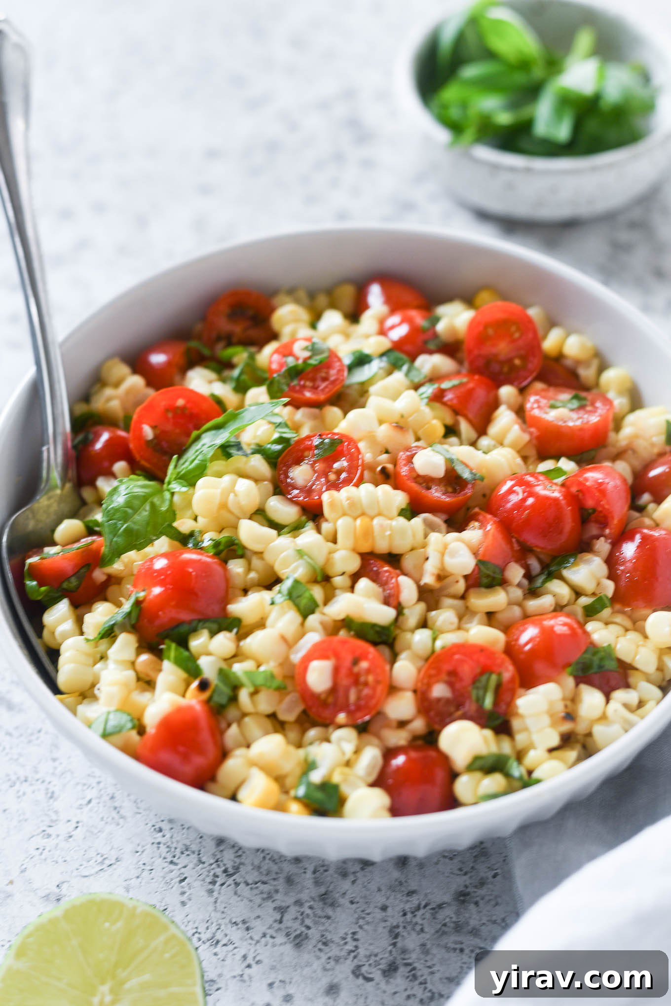 Spoon buried in a bowl of corn and tomato salad