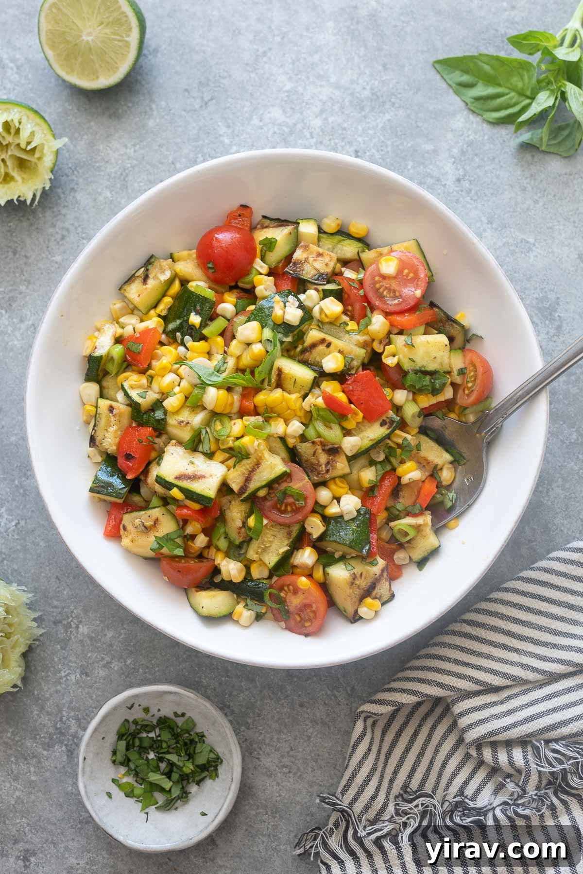 Grilled zucchini and corn salad in a bowl with serving spoon.