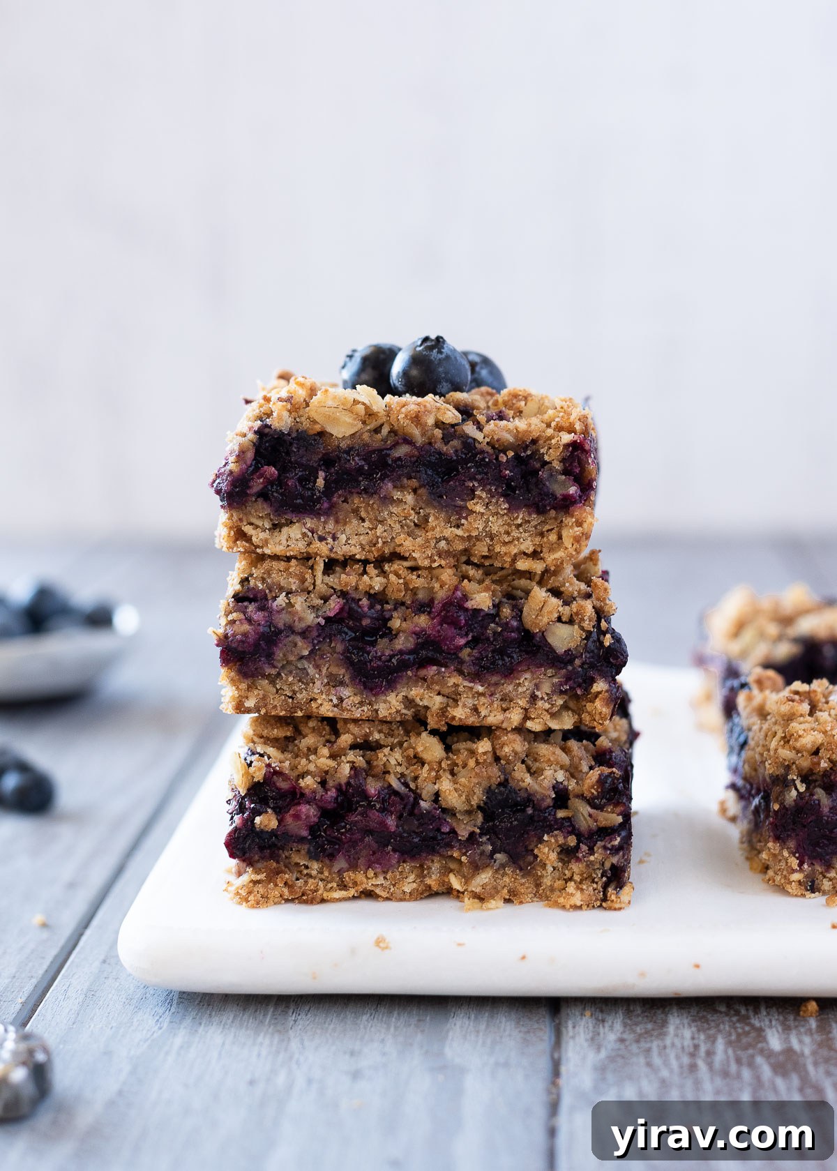 Blueberry crumble bars stacked up with blueberries on top