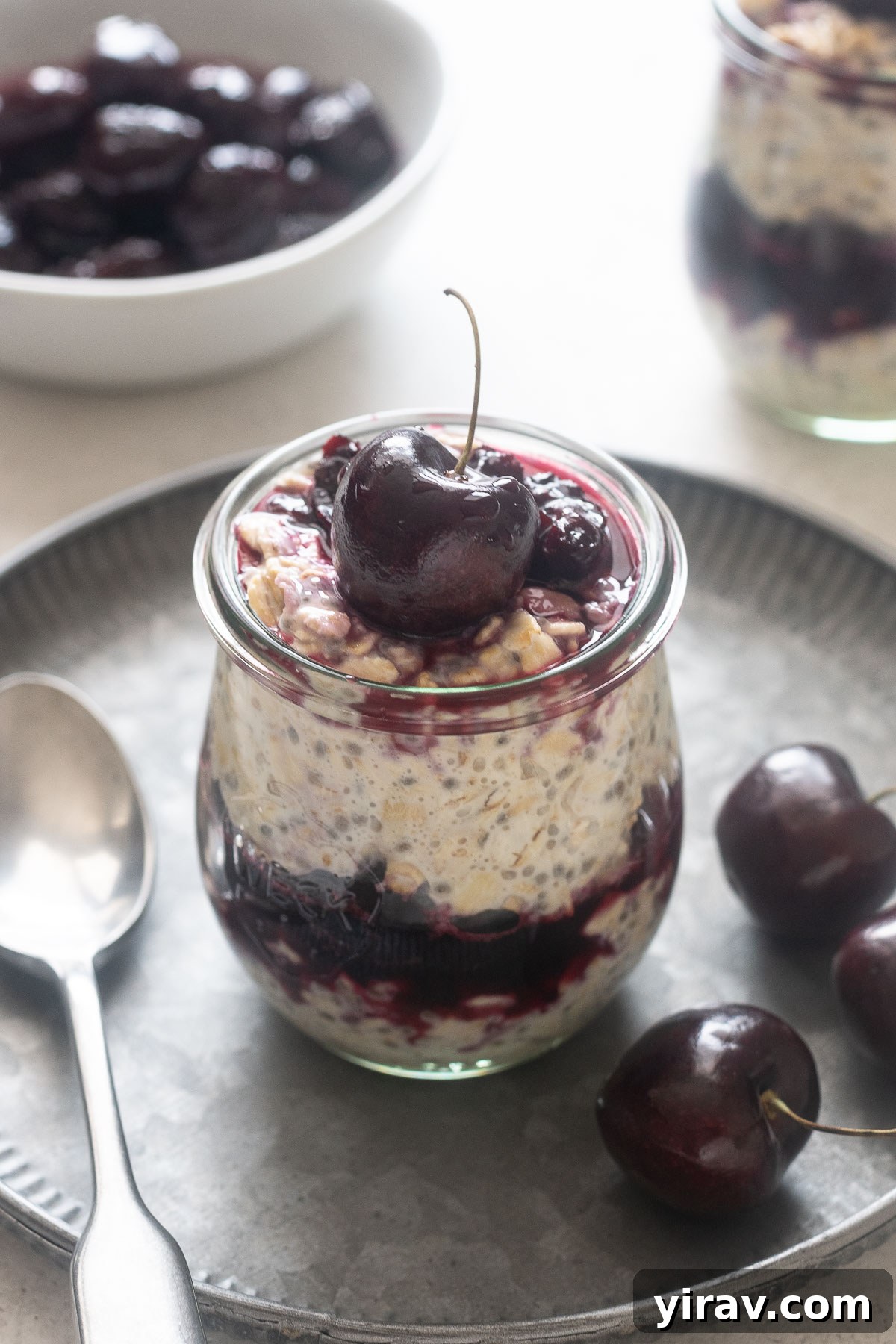 Cherry pie overnight oats in a jar with a cherry on top.