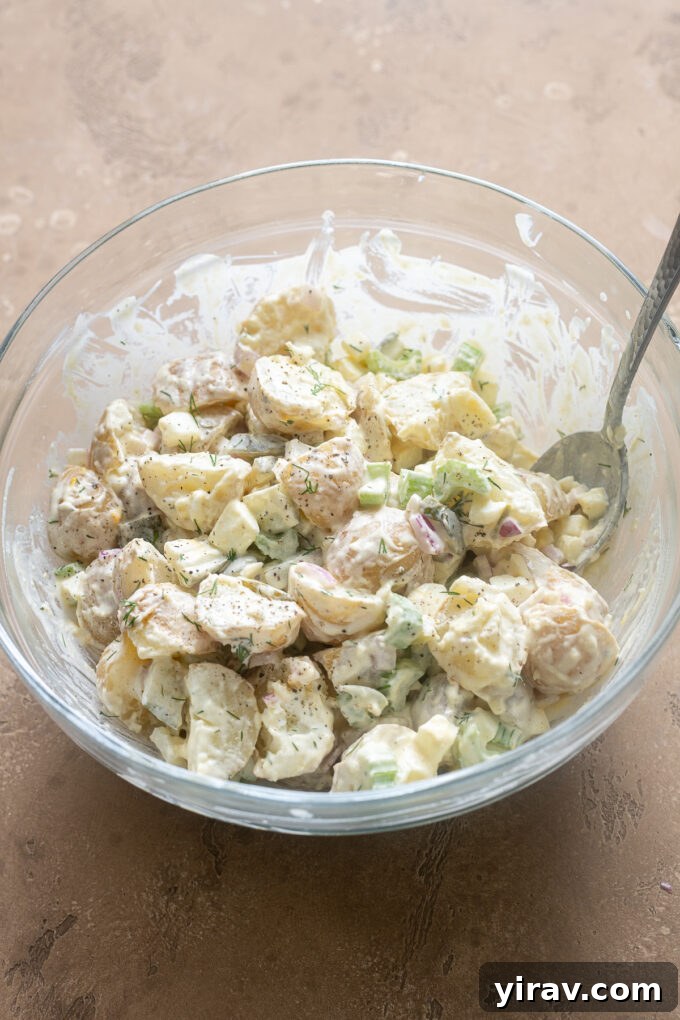 Potato salad with dill pickles in a mixing bowl.