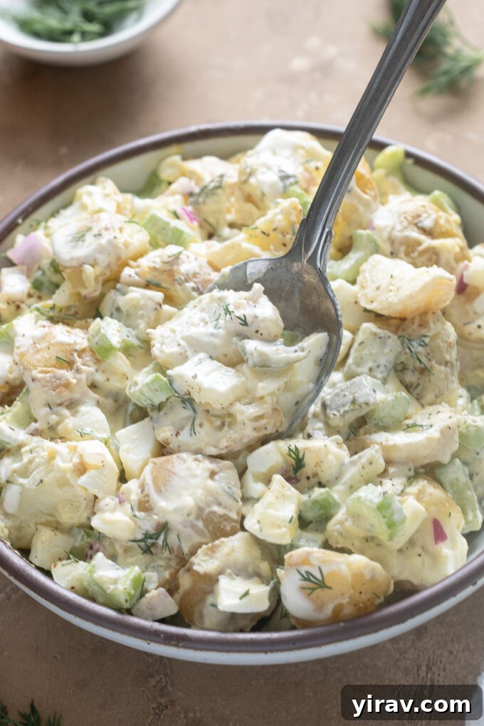 Serving spoon full of dill pickle potato salad.