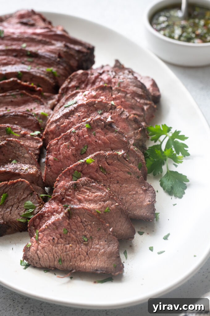 Perfectly sliced Santa Maria grilled tri tip roast on a platter, garnished with fresh herbs and ready to serve.