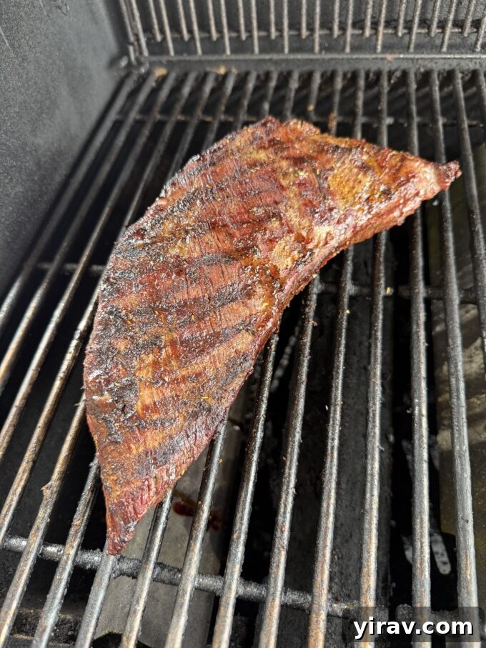 Tri tip roast cooking over indirect heat on a gas grill, maintaining an even temperature.