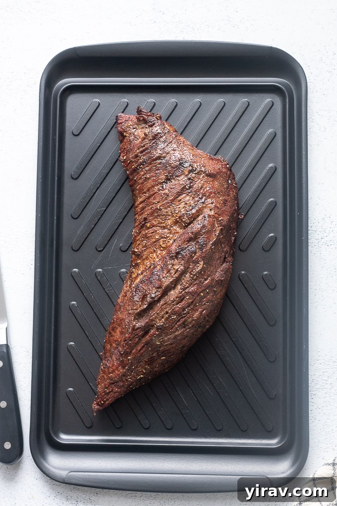 Santa Maria grilled tri tip resting on a wooden cutting board after being removed from the grill.