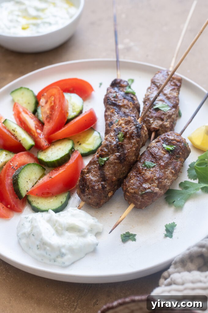 Flavorful lamb kofta kebabs on a plate, served with tzatziki and fresh vegetables.