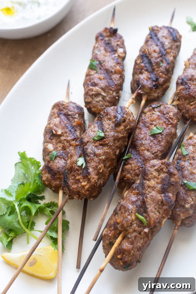 Freshly grilled lamb kofta kebabs arranged on a serving platter with wooden skewers.
