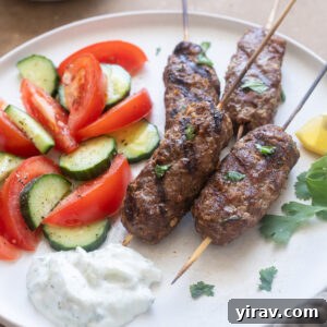 Lamb kofta kebabs on a plate with tzatziki and vegetables.