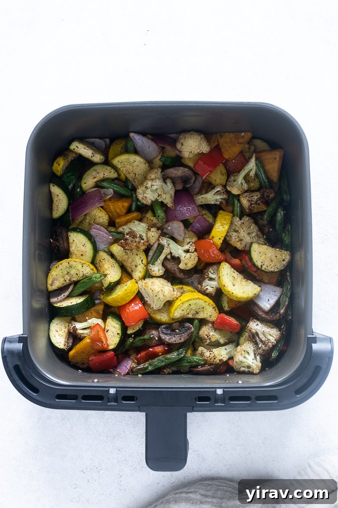 Golden-brown, roasted vegetables cooking inside an air fryer.