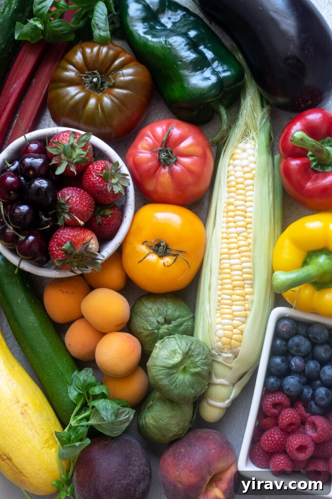 A vibrant selection of July seasonal produce, including ripe red tomatoes, yellow corn on the cob, fresh green zucchini, and other colorful summer vegetables and fruits.
