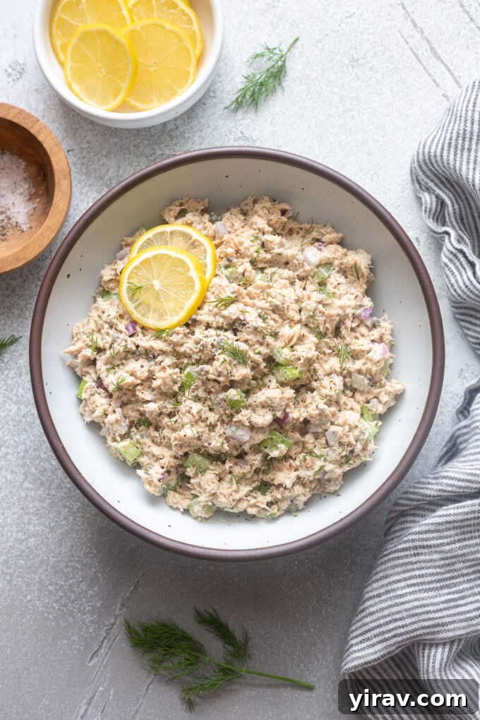 Salad with canned salmon in a bowl with lemon slices and dill.