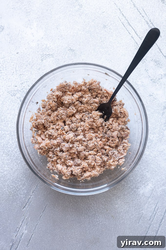 Mashed canned salmon in a medium bowl.