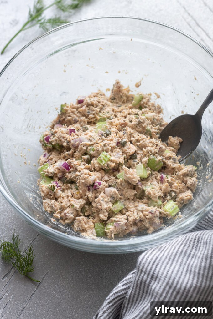 Salmon salad in a mixing bowl with a spoon.