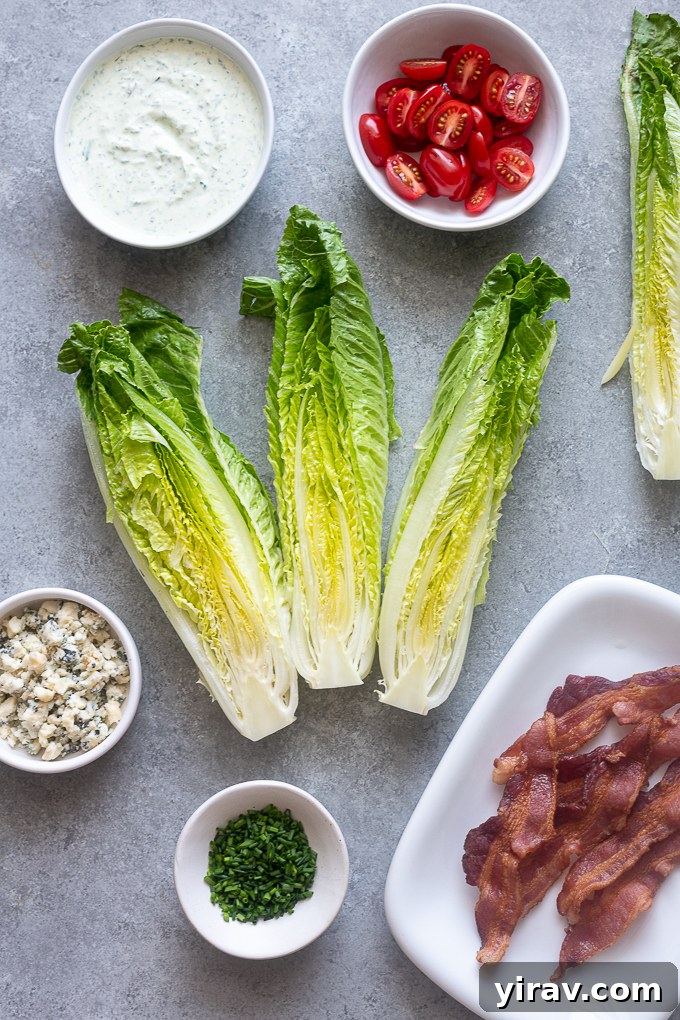 All ingredients for Romaine Wedge Salad prepped and laid out, including cooked bacon, halved cherry tomatoes, crumbled blue cheese, and fresh chives.