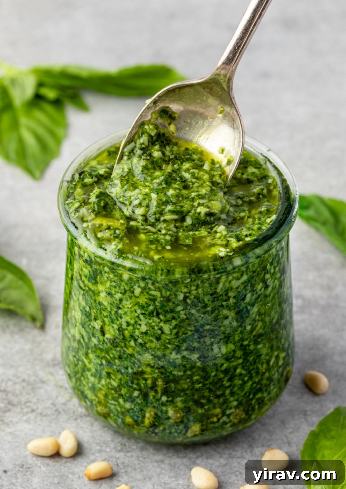 Basil pesto in a jar with a spoon.