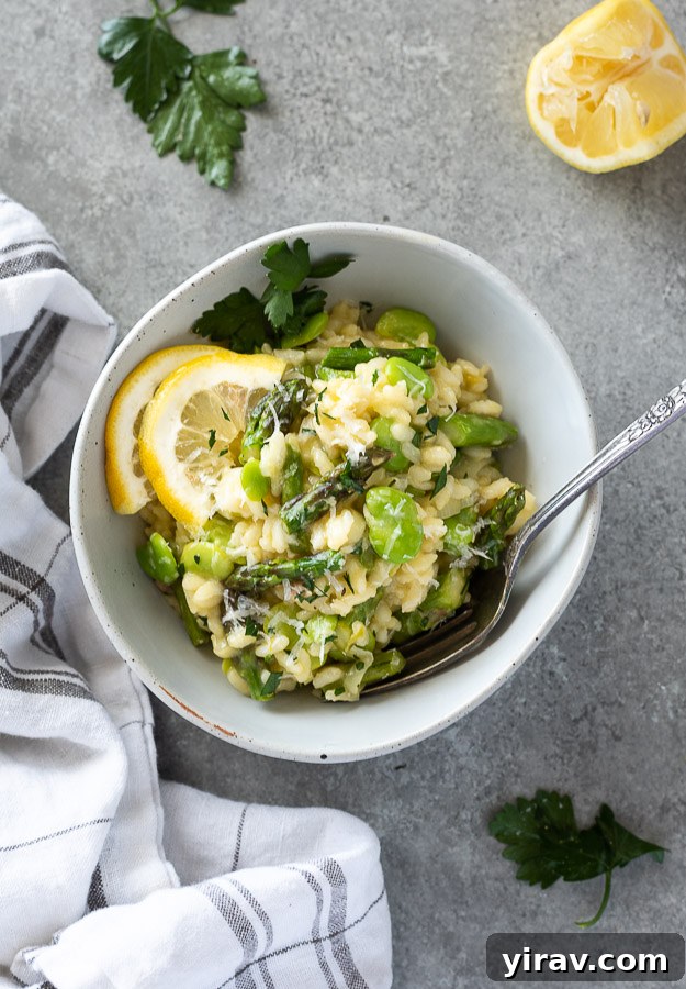 Spring risotto in a bowl with a fork, garnished with lemon and parsley.