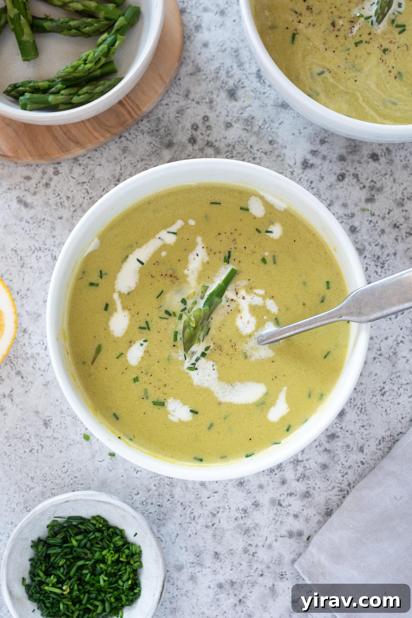 Creamy asparagus soup in a bowl with chives on top.
