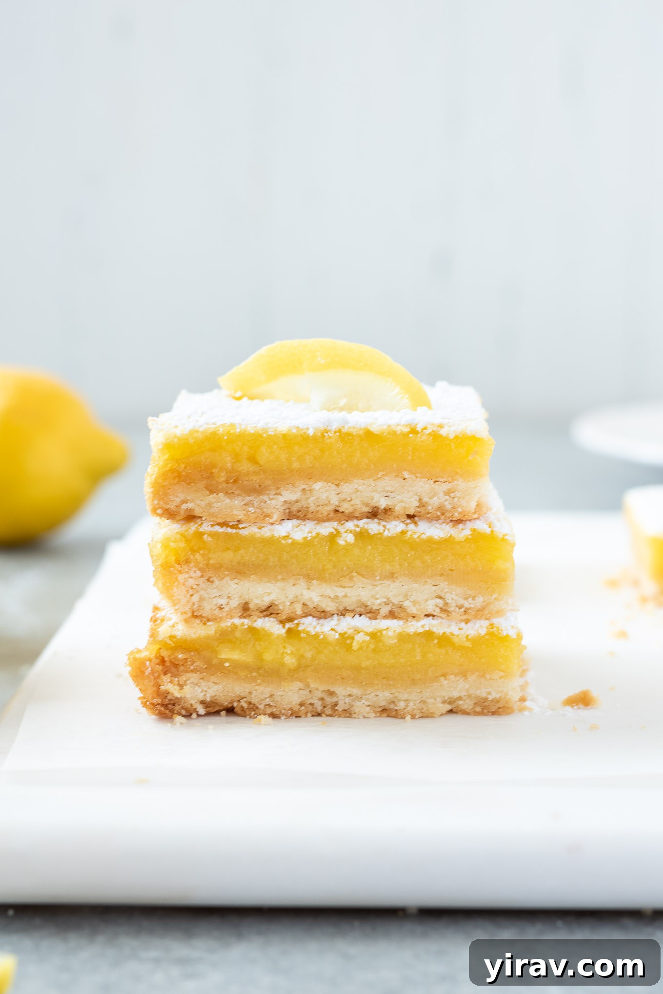 Stack of lemon bars on a platter, dusted with powdered sugar.