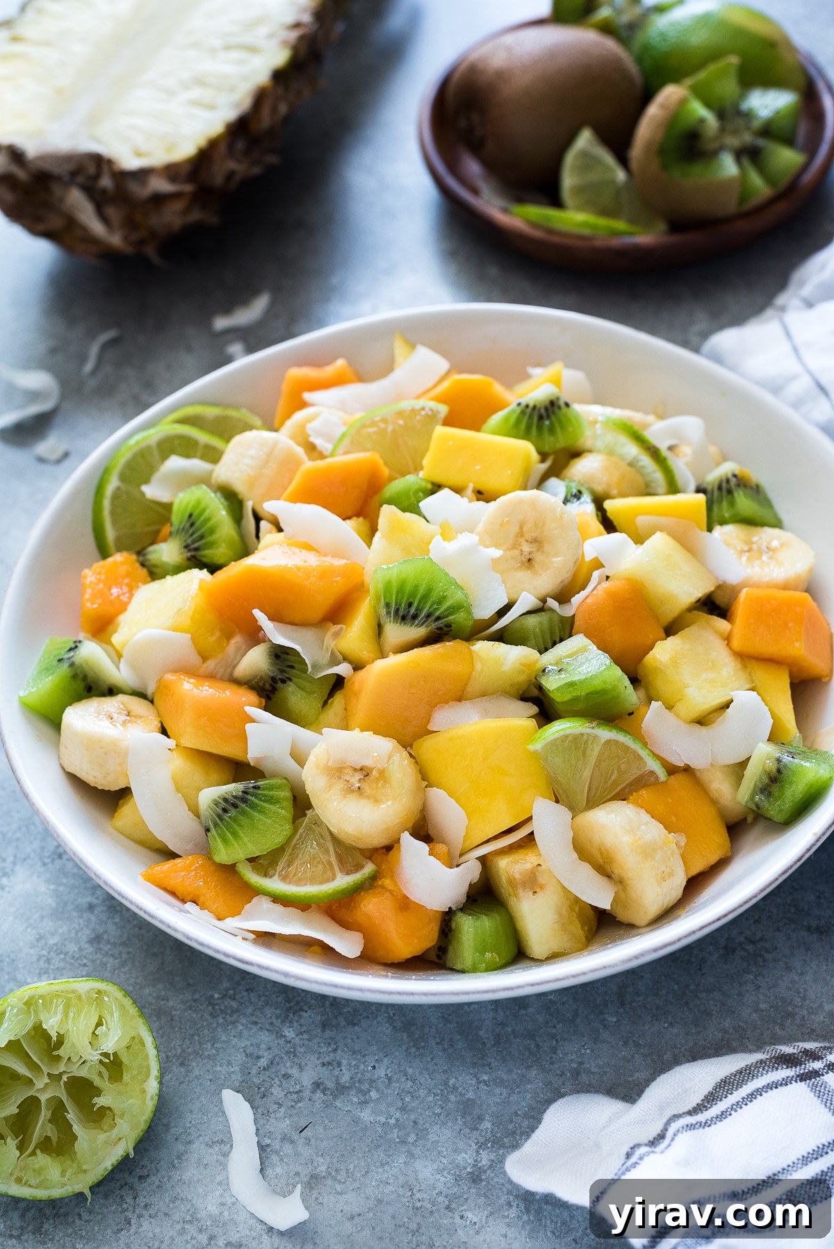 Tropical fruit salad with coconut flakes in a serving bowl.