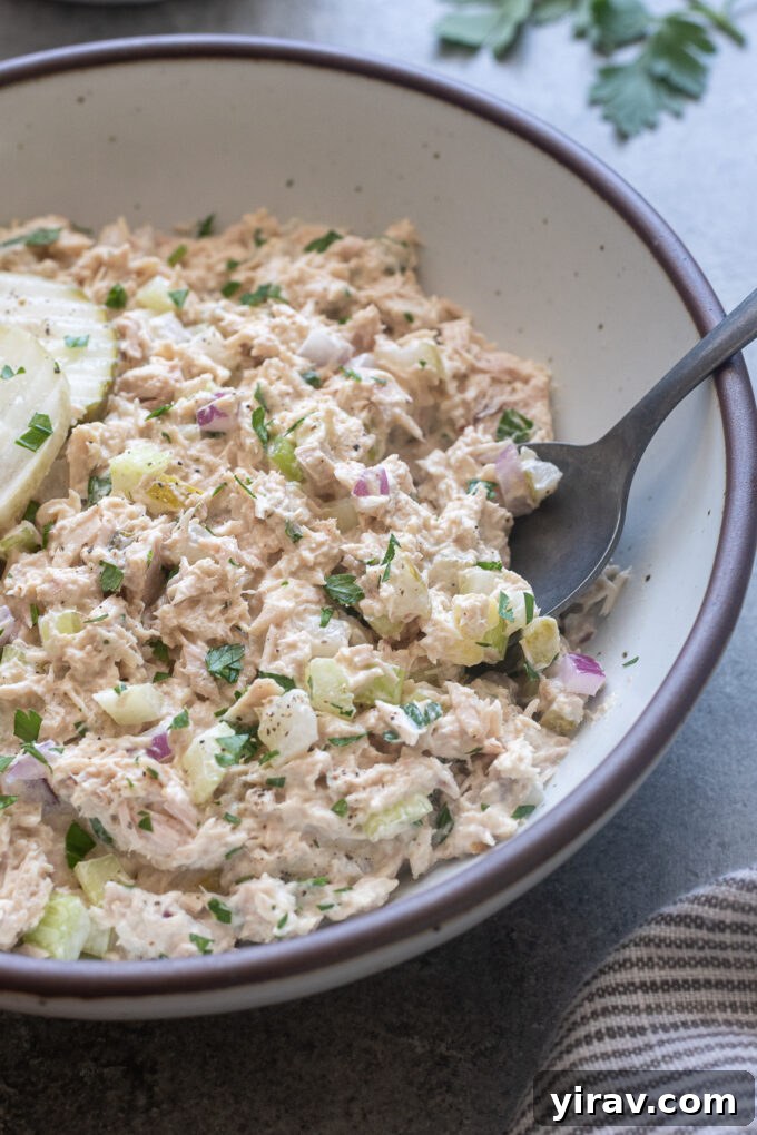 Zesty Dill Pickle Tuna 7 A bowl of freshly made dill pickle tuna salad, fully combined and ready for serving, with a spoon for tasting.