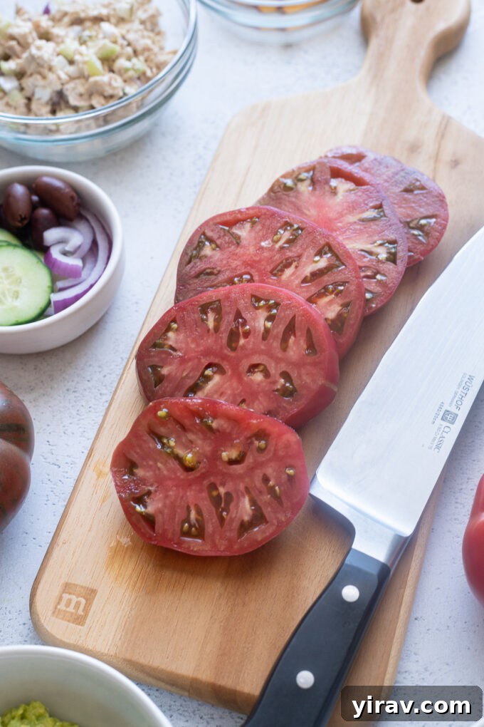 Assorted sliced heirloom tomatoes arranged on a rustic wooden board, ready for creative toppings.