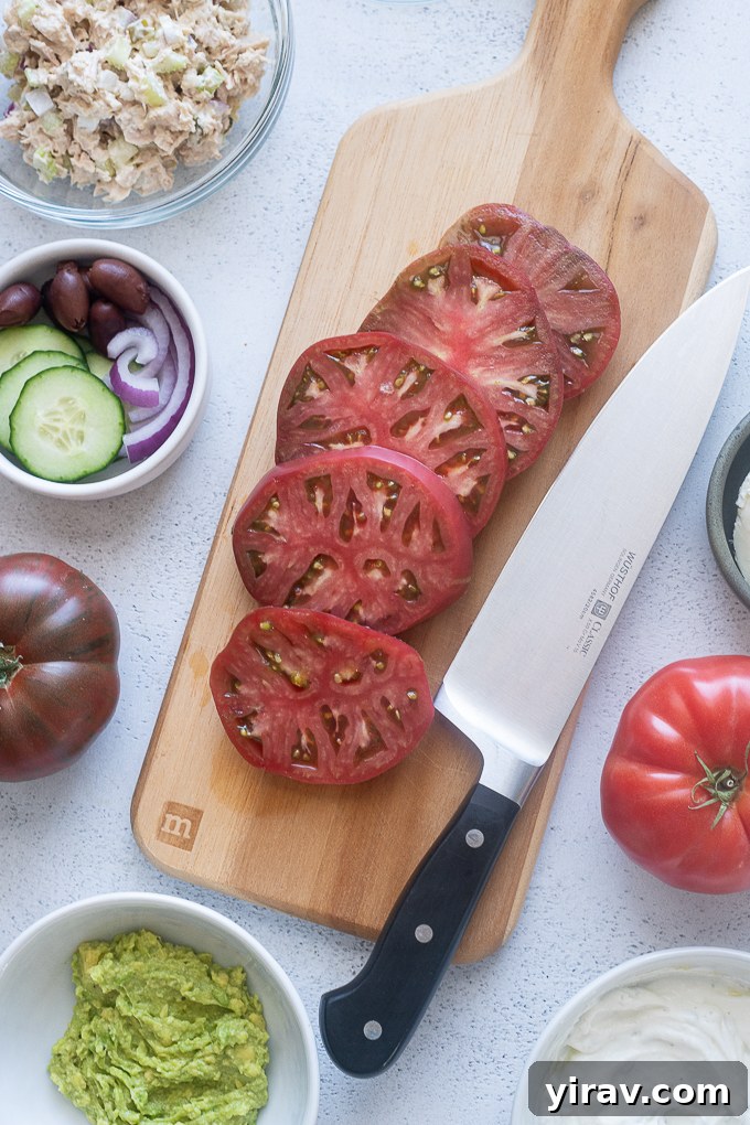 Thickly sliced heirloom tomatoes laid out on a wooden cutting board, ready for preparation.