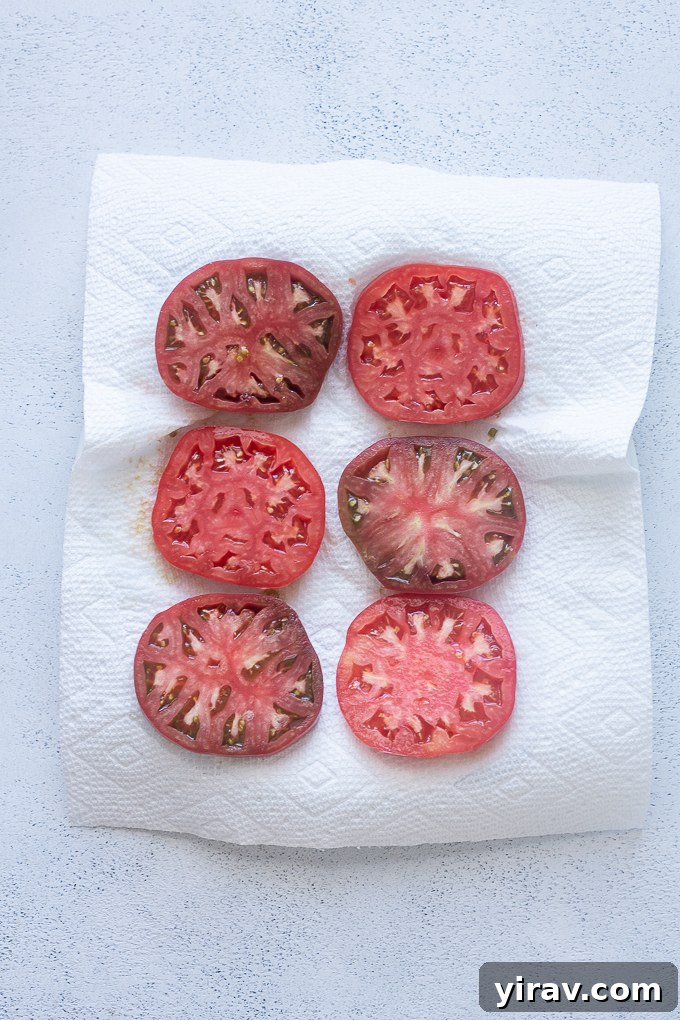 Slices of heirloom tomato carefully arranged on paper towels to absorb excess moisture.